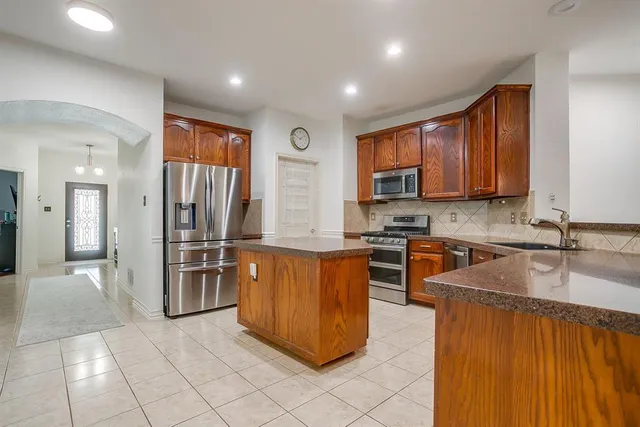 a kitchen with stainless steel appliances granite countertop a refrigerator and a stove top oven