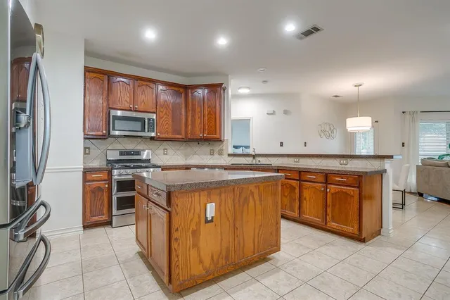 a kitchen with stainless steel appliances granite countertop a stove a sink a refrigerator and a microwave