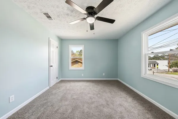 an empty room with windows and fan