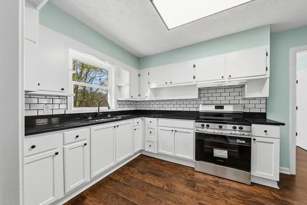 a kitchen with granite countertop white cabinets and white appliances