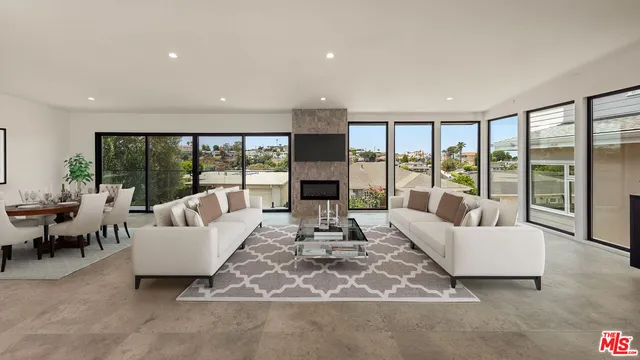 a living room with furniture large windows and a fireplace