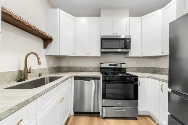 a kitchen with granite countertop white cabinets and stainless steel appliances