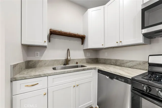 a kitchen with granite countertop white cabinets and a stove