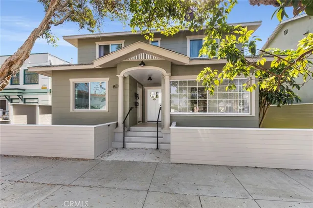 a view of a white house with large windows and a small yard