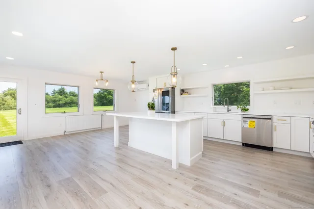 a large white kitchen with kitchen island white cabinets and wooden floor