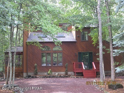 a view of a brick house with a yard plants and large tree