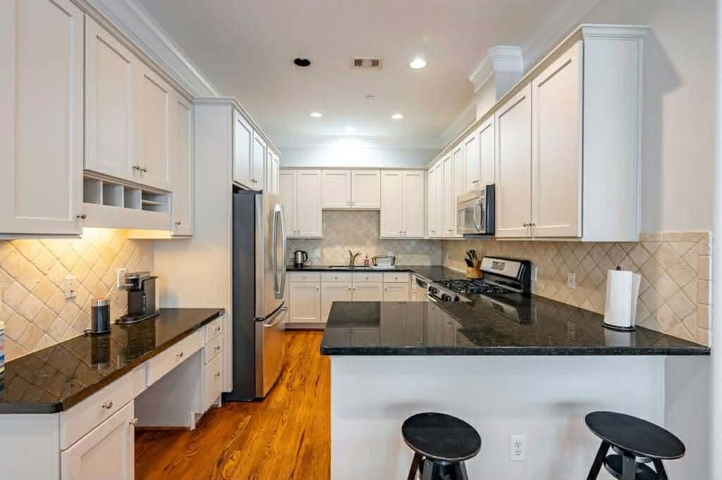 2210 Mid Lane, Unit 107 Houston, TX 77027 - Photo 6 of 15 a kitchen with stainless steel appliances a stove a sink a stove top oven a counter space and cabinets