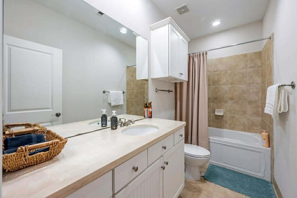 2210 Mid Lane, Unit 107 Houston, TX 77027 - Photo 10 of 15 a bathroom with a granite countertop sink a toilet a mirror and shower