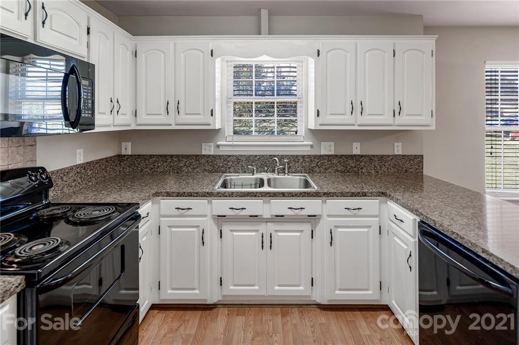 8577 Unity Church Road Denver, NC 28037 - Photo 11 of 33 a kitchen with granite countertop white cabinets and a stove top oven