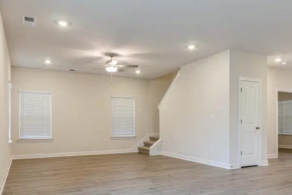 an empty room with wooden floor and windows