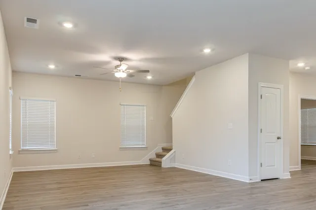 an empty room with wooden floor and windows