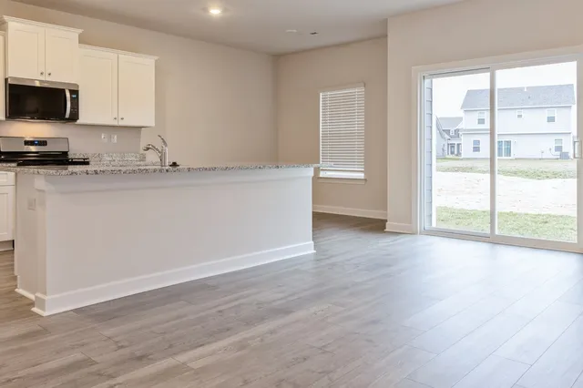 a view of kitchen with stainless steel appliances granite countertop a stove a sink and a large window