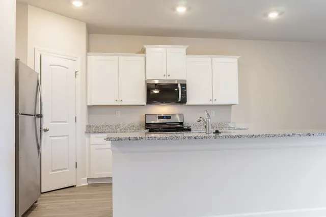 a kitchen with stainless steel appliances granite countertop a stove a sink and a refrigerator