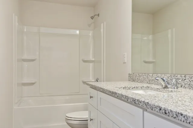 a bathroom with a granite countertop sink a toilet and shower