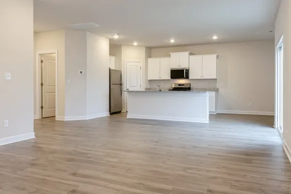 a view of a kitchen with kitchen island a sink wooden floor and a refrigerator