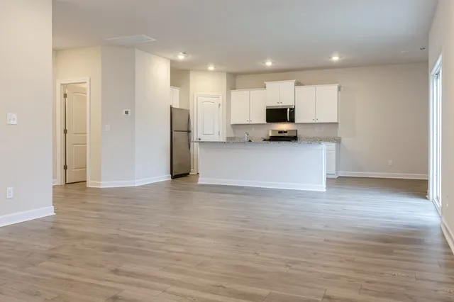 a view of a kitchen with kitchen island a sink wooden floor and a refrigerator
