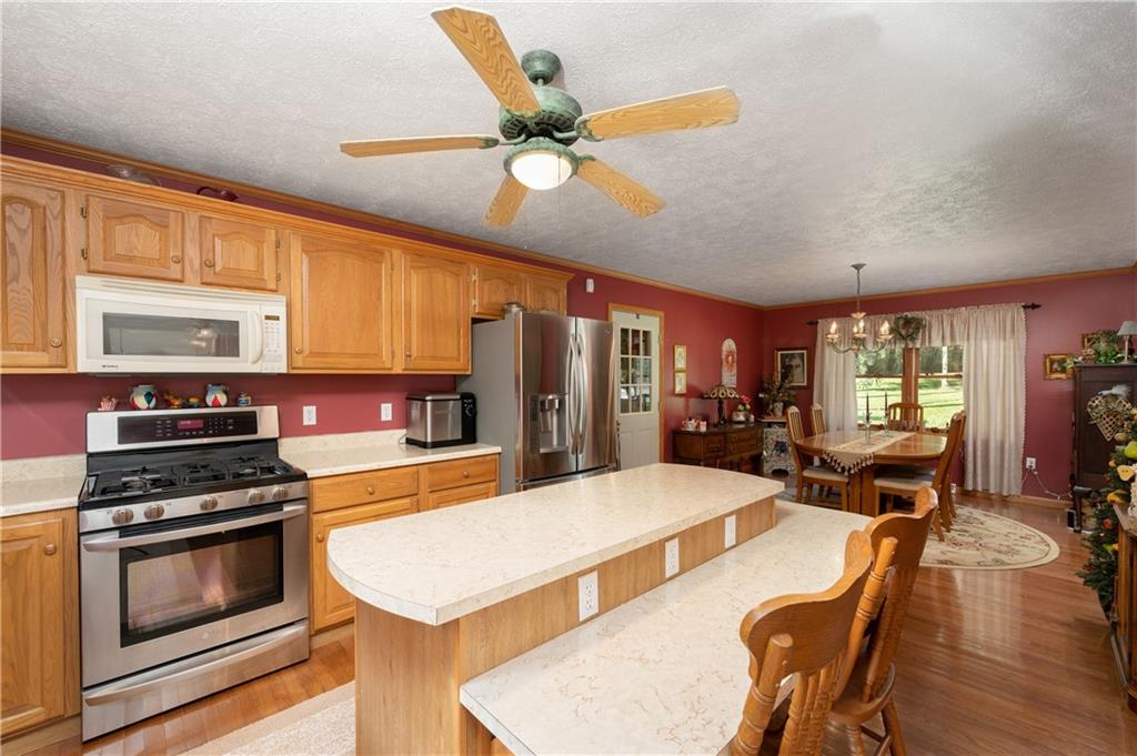 360 Sopher Road Grove City, PA 16127 - Photo 5 of 25 a kitchen with stainless steel appliances kitchen island granite countertop a stove top oven a sink a dining table and chairs with wooden floor