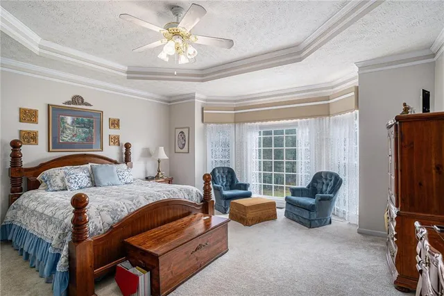 a large bed sitting in a bedroom next to a window and a chandelier