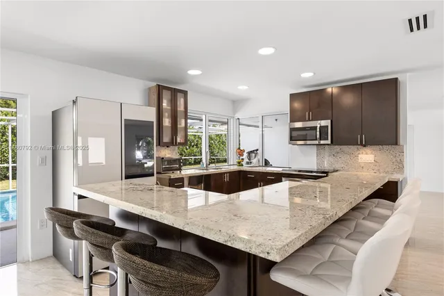 a kitchen with granite countertop a table chairs microwave and cabinets