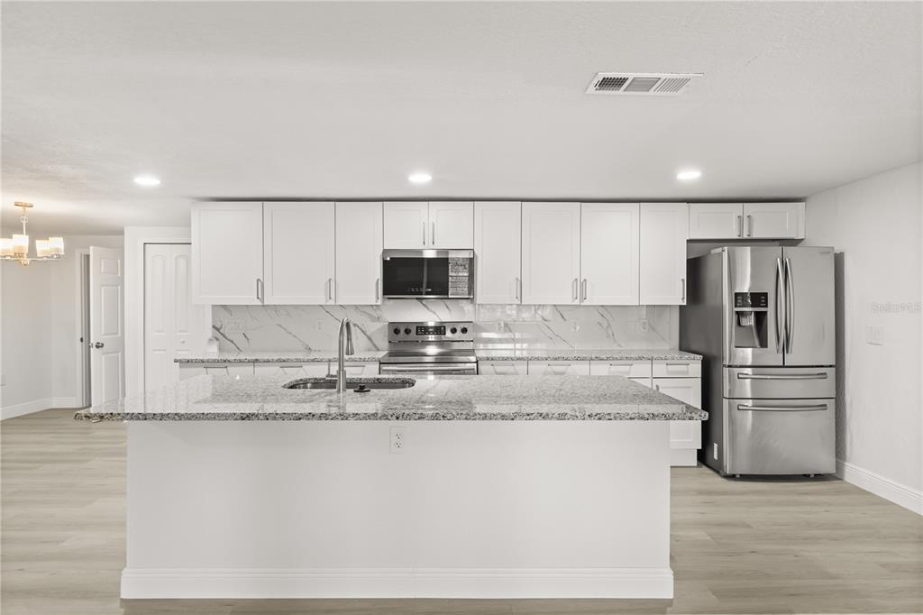 1251 Northwest 23rd Avenue Ocala, FL 34475 - Photo 5 of 34 a large kitchen with stainless steel appliances granite countertop a stove a sink and a refrigerator