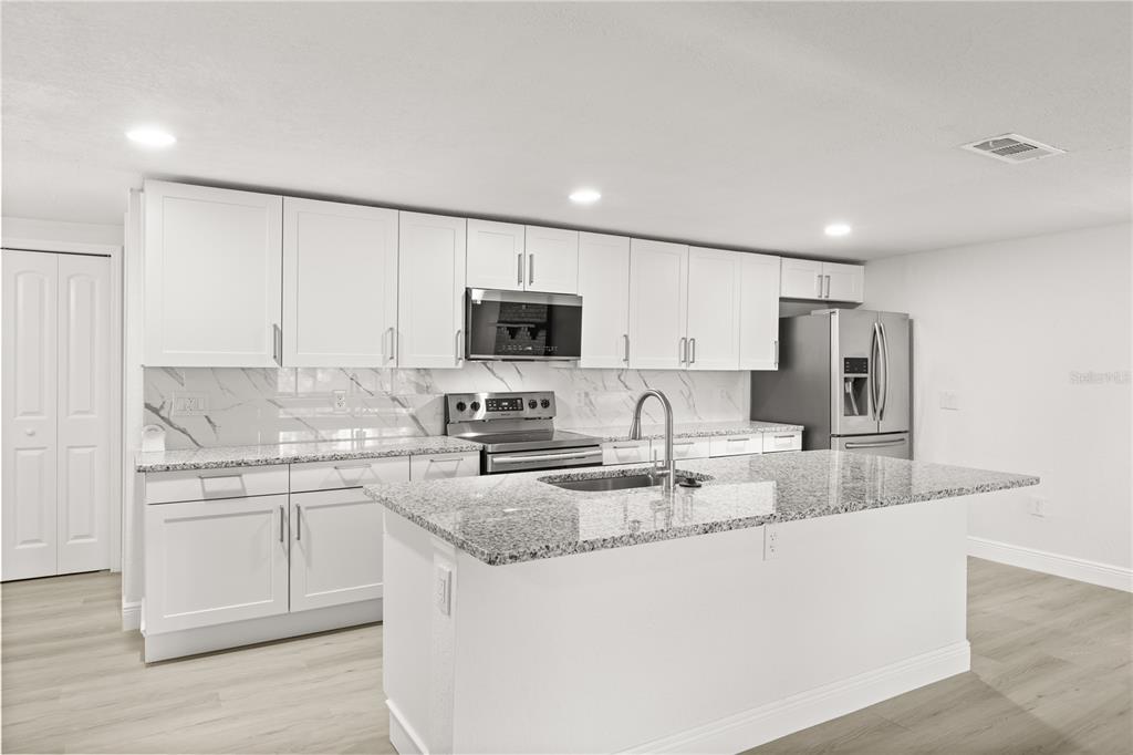 1251 Northwest 23rd Avenue Ocala, FL 34475 - Photo 6 of 34 a large kitchen with granite countertop a sink a stove a oven a counter space and cabinets