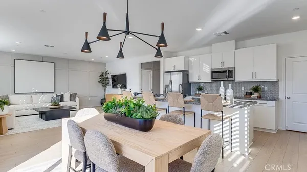 a kitchen with stainless steel appliances kitchen island granite countertop a dining table chairs and white cabinets