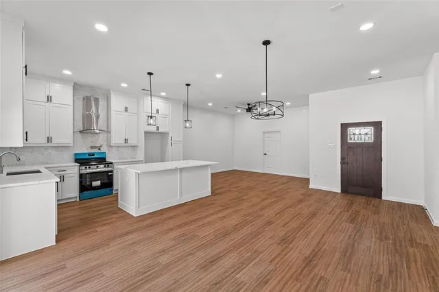 a large kitchen with granite countertop a large counter top a sink stainless steel appliances and cabinets