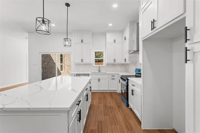 a large kitchen with stainless steel appliances granite countertop a white stove top oven and a chandelier