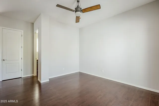 an empty room with wooden floor cabinet and windows