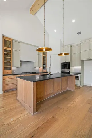 a kitchen with stainless steel appliances granite countertop a sink a stove and a wooden floors