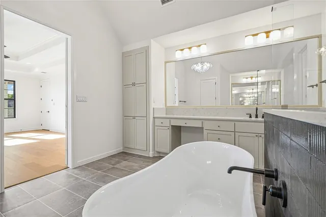 a en suite bathroom with a double vanity sink a mirror and a bathtub