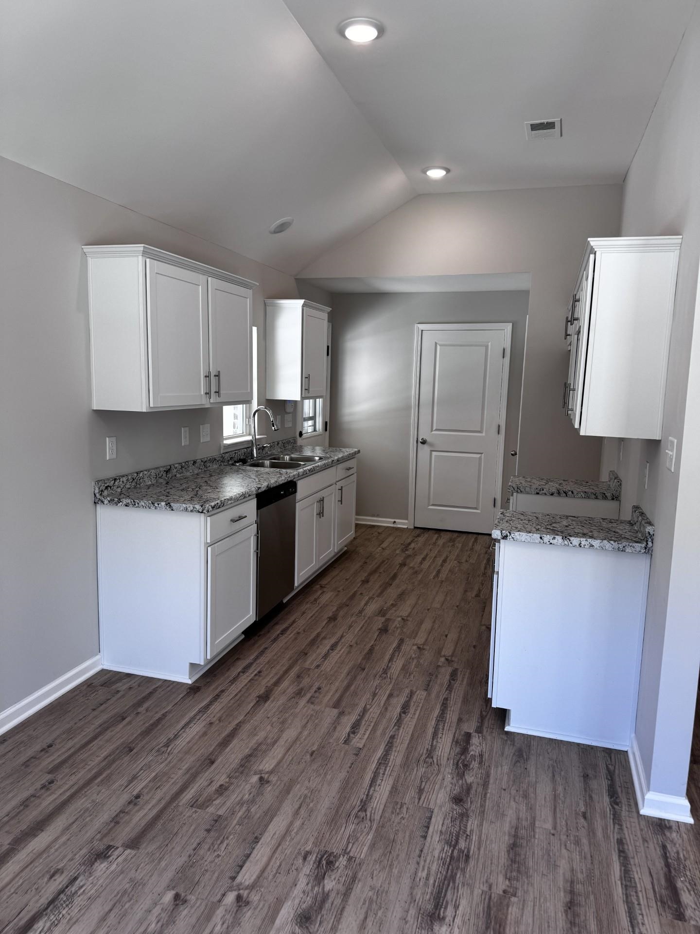 5243 Zodiac Road Memphis, TN 38118 - Photo 7 of 10 Kitchen with white cabinets, light stone counters, vaulted ceiling, dishwasher, and dark wood-style flooring