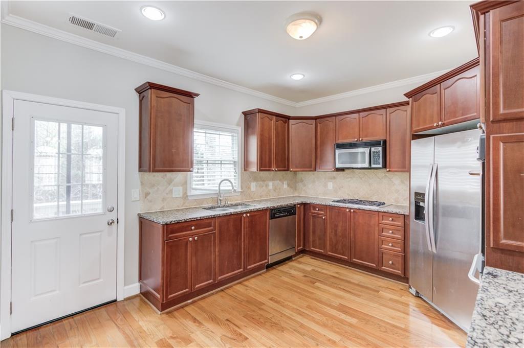 11007 Lorin Way Duluth, GA 30097 - Photo 12 of 30 a kitchen with stainless steel appliances granite countertop a refrigerator and wooden cabinets