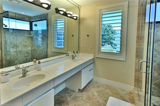a bathroom with a granite countertop sink a mirror and a shower
