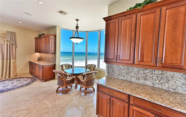 a kitchen with granite countertop a sink dishwasher a dining table and chairs with wooden floor