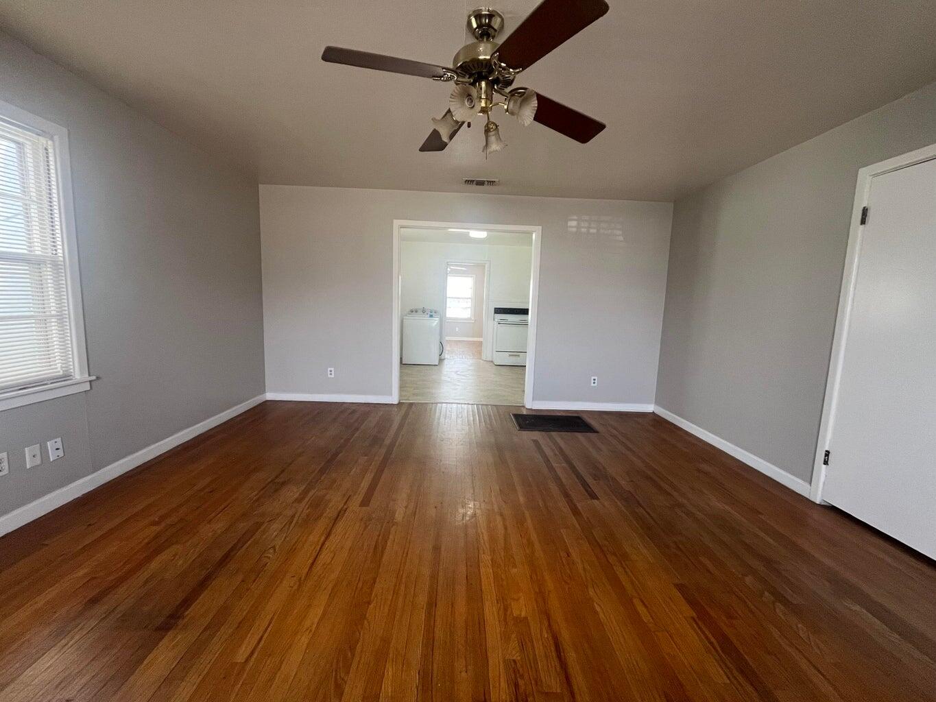 3113 33rd Street, Unit A Lubbock, TX 79410 - Photo 3 of 10 a view of empty room with wooden floor and ceiling fan
