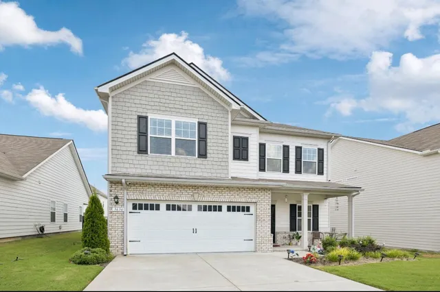 a view of a white house with a small yard and potted plants