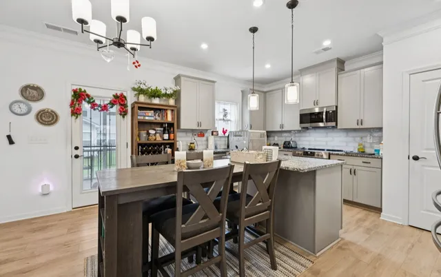 a kitchen with granite countertop center island a sink dishwasher a dining table and chairs with wooden floor
