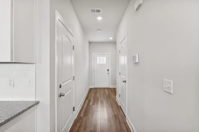 a view of a hallway with wooden floor and a bathroom