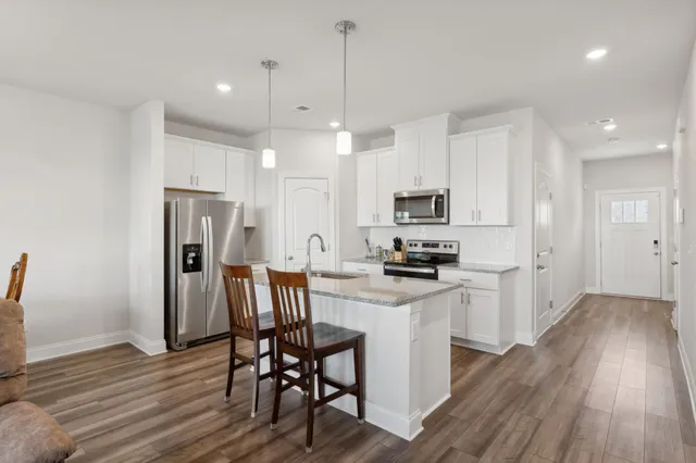 a kitchen with stainless steel appliances a dining table chairs microwave and refrigerator