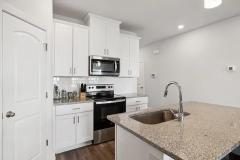 a kitchen with white cabinets a sink and appliances