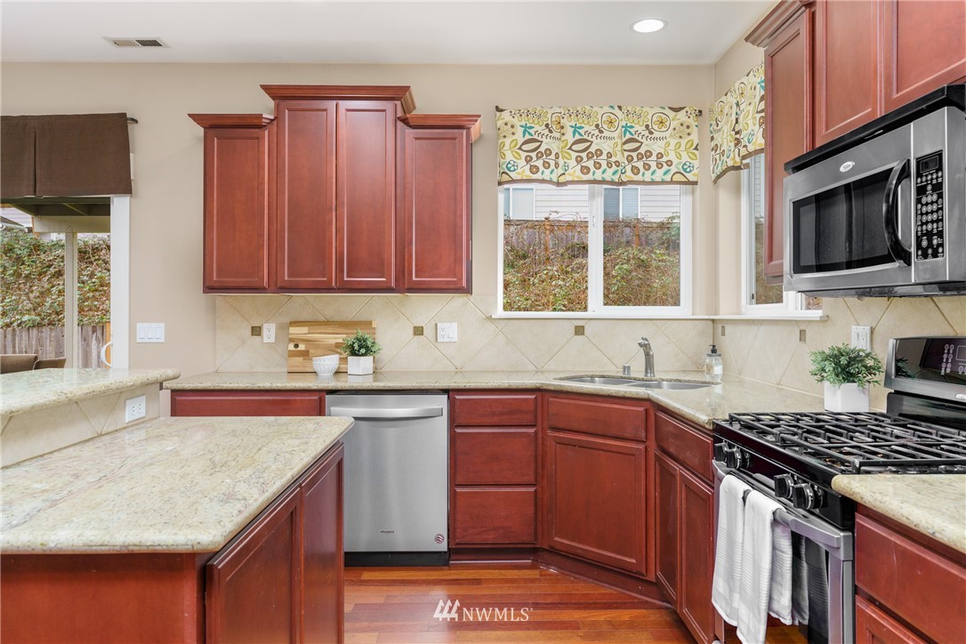 883 Jericho Place Northeast Renton, WA 98059 - Photo 12 of 30 a kitchen with stainless steel appliances granite countertop a sink stove and microwave