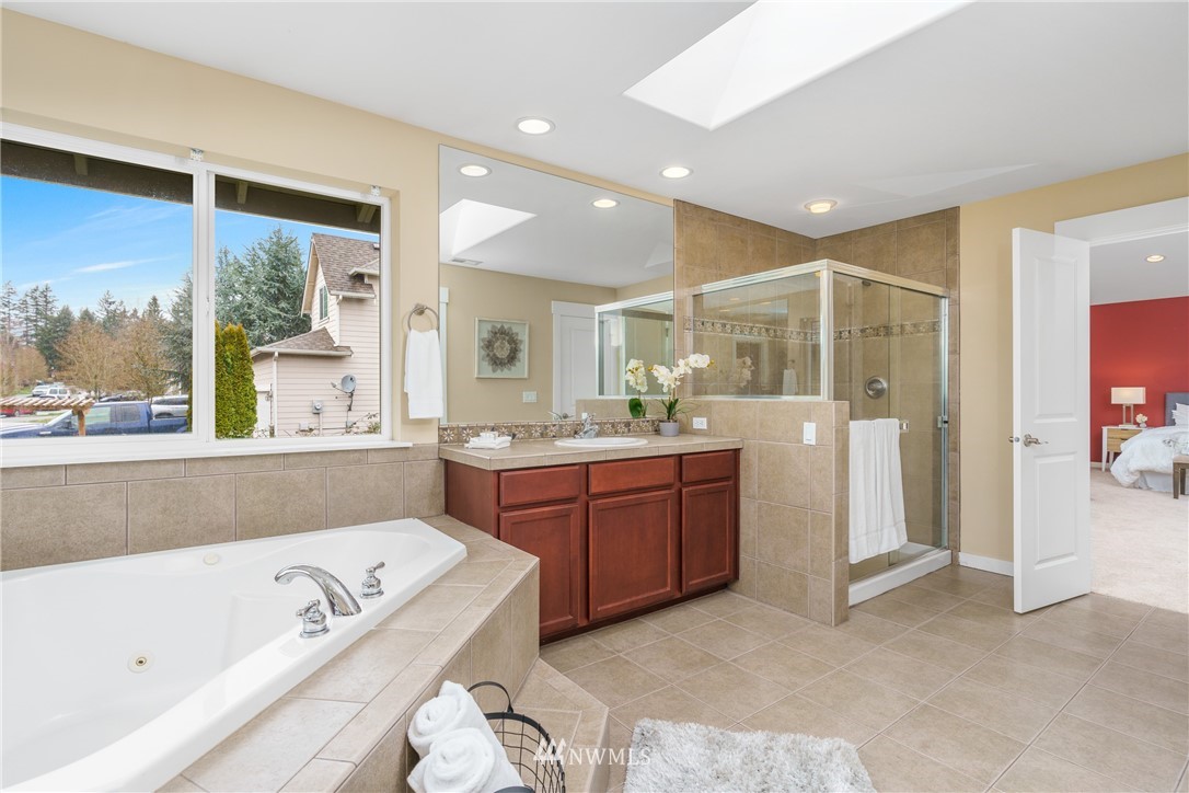 883 Jericho Place Northeast Renton, WA 98059 - Photo 21 of 30 a bathroom with a tub a sink and a large mirror