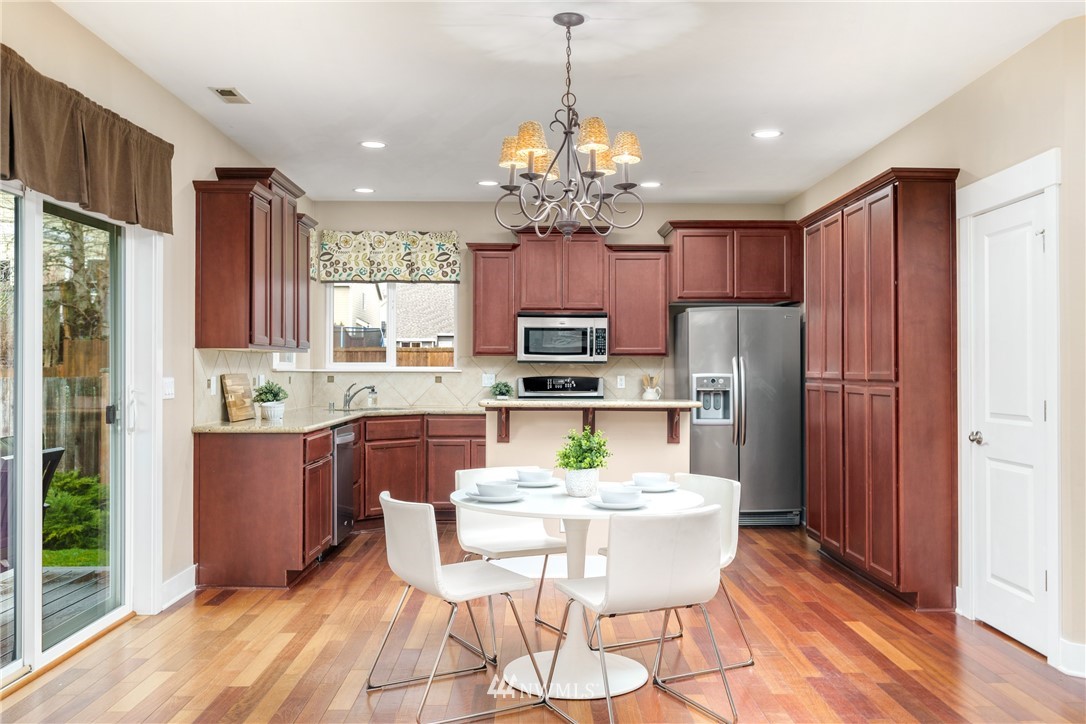 883 Jericho Place Northeast Renton, WA 98059 - Photo 9 of 30 a kitchen with stainless steel appliances granite countertop a refrigerator a stove top oven a sink dishwasher and a dining table with wooden floor