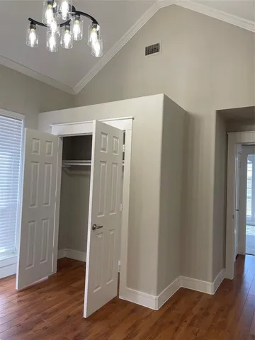 an empty room with wooden floor closet and windows