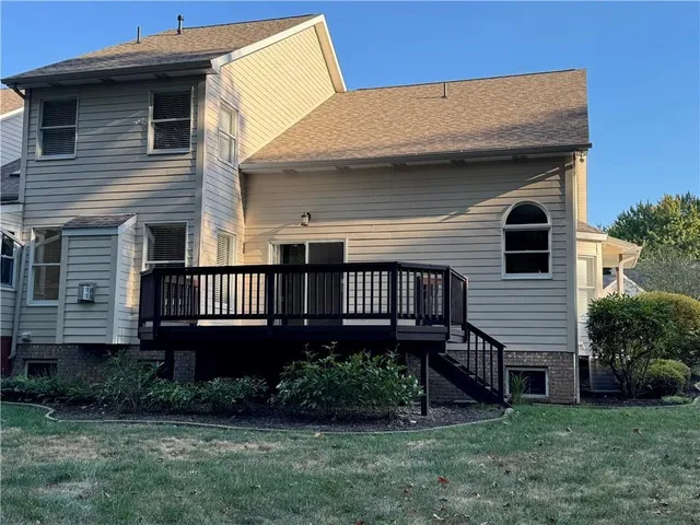 a view of a house with a yard plants and large tree