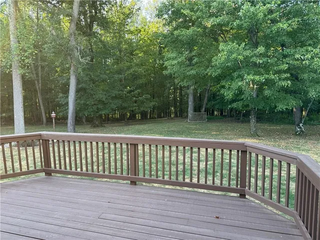 a view of wooden deck and a yard with wooden fence
