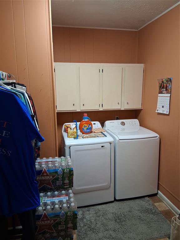 407 North Files Street Itasca, TX 76055 - Photo 17 of 30 Laundry area with cabinet space, washer and dryer, and wooden walls