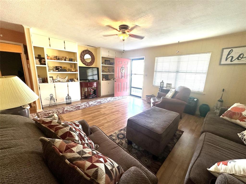 407 North Files Street Itasca, TX 76055 - Photo 2 of 30 Living area featuring wood finished floors, a textured ceiling, and ceiling fan