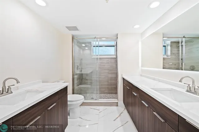 a bathroom with a granite countertop sink a toilet a mirror and shower